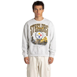 A man modeling a light gray heather crewneck sweatshirt with a Pittsburgh Steelers graphic on the front, paired with off-white cargo pants, against a plain light gray background.
